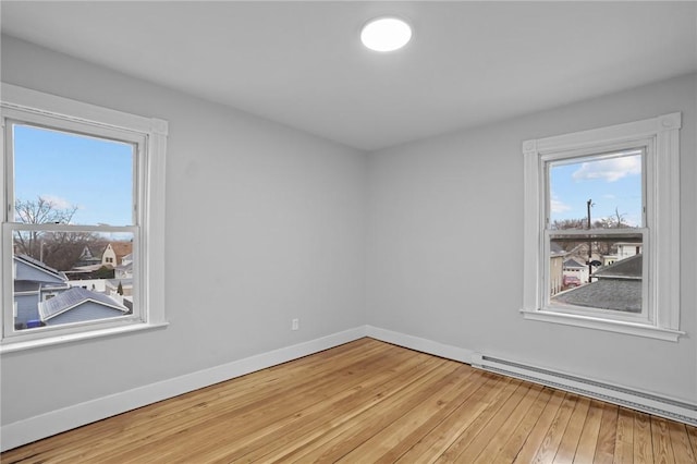 unfurnished room featuring light wood-type flooring and a baseboard heating unit