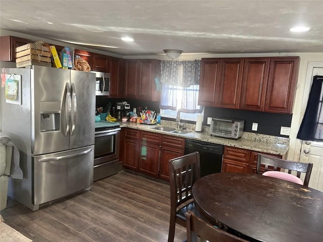 kitchen featuring appliances with stainless steel finishes, sink, dark wood-type flooring, and light stone counters