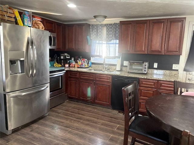 kitchen with appliances with stainless steel finishes, sink, light stone counters, and dark hardwood / wood-style floors