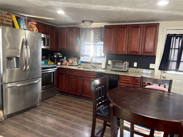 kitchen with dark hardwood / wood-style floors, appliances with stainless steel finishes, sink, and light stone counters