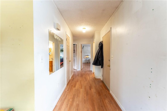 hallway featuring light wood-type flooring and a textured ceiling