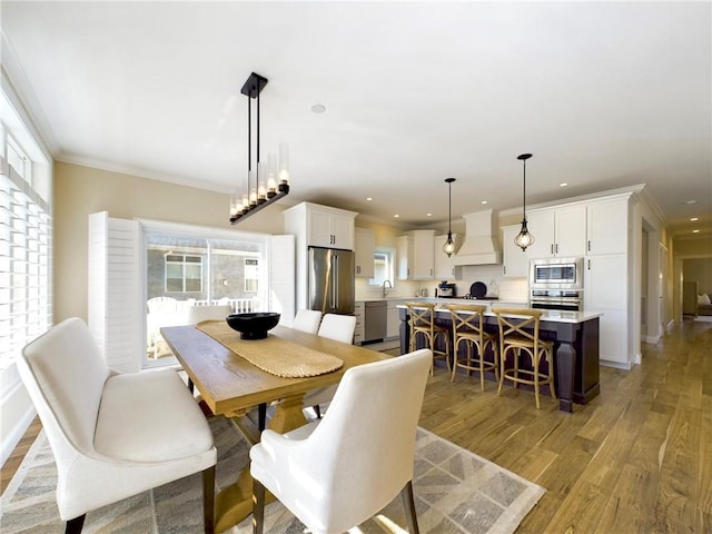 dining area featuring ornamental molding, sink, and light hardwood / wood-style flooring