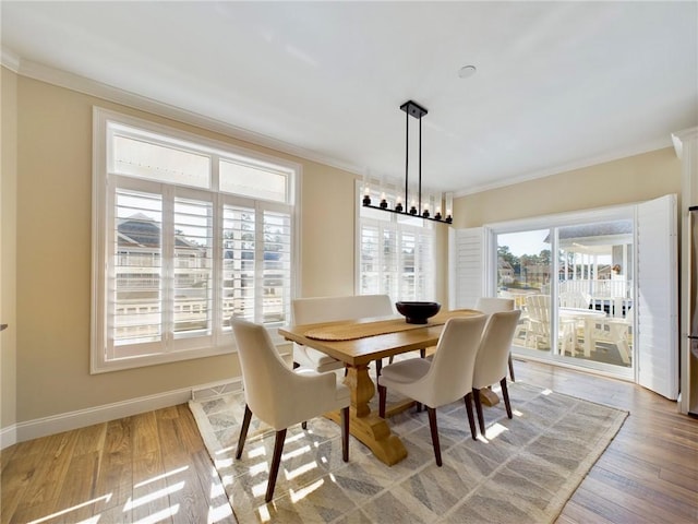 dining space featuring an inviting chandelier, ornamental molding, and light hardwood / wood-style floors