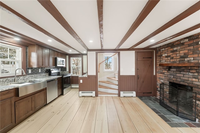 kitchen with baseboard heating, stainless steel appliances, sink, and beamed ceiling