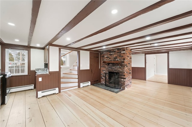 unfurnished living room with a baseboard heating unit, a fireplace, beamed ceiling, and light wood-type flooring