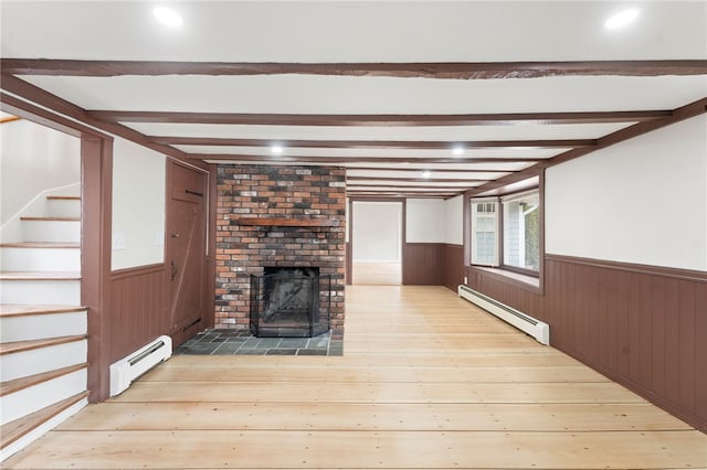 unfurnished living room with beamed ceiling, a brick fireplace, a baseboard heating unit, and light wood-type flooring