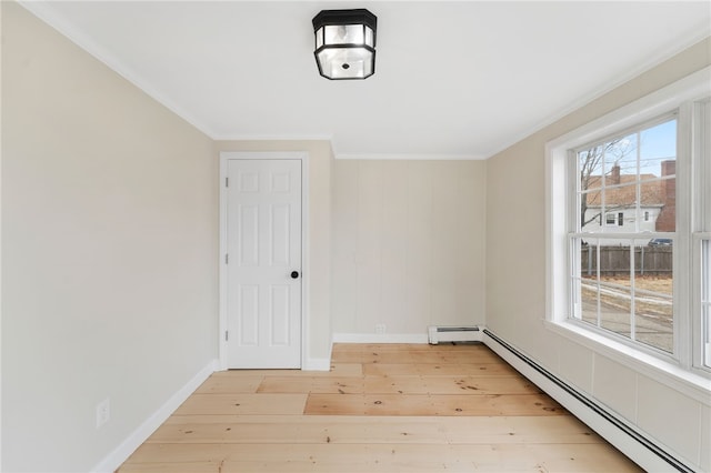 spare room with a baseboard heating unit, crown molding, and light hardwood / wood-style floors