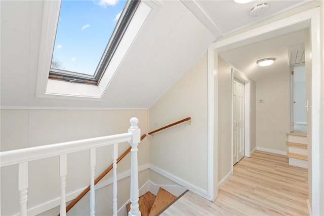 staircase featuring hardwood / wood-style flooring and vaulted ceiling with skylight