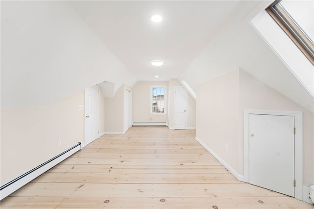 additional living space with a baseboard radiator, lofted ceiling, and light wood-type flooring