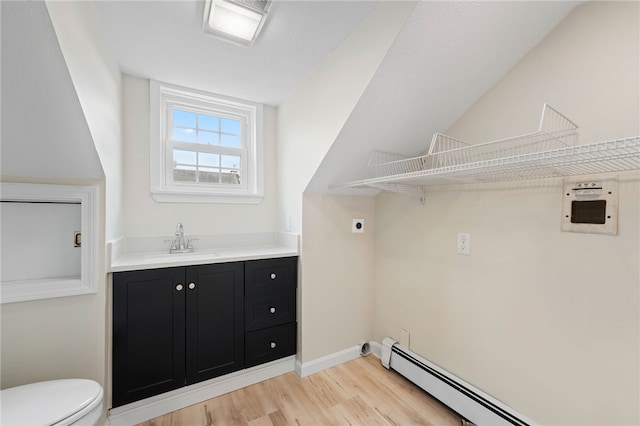 laundry room with baseboard heating, light wood-type flooring, sink, and electric dryer hookup