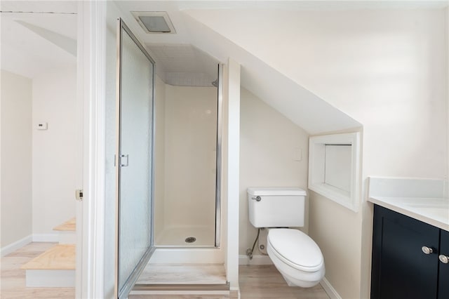 bathroom featuring wood-type flooring, lofted ceiling, vanity, toilet, and a shower with door