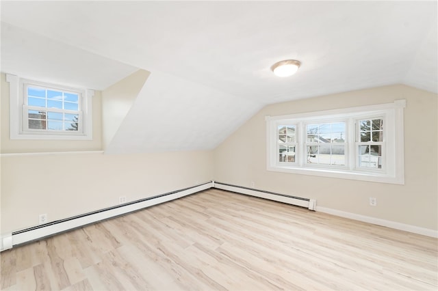 additional living space featuring vaulted ceiling, baseboard heating, and light hardwood / wood-style flooring