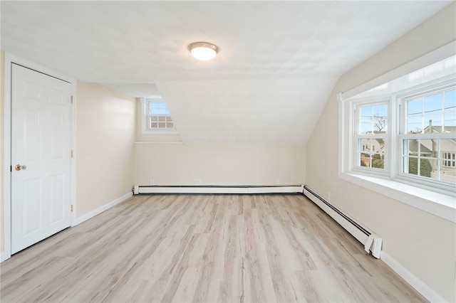 additional living space with vaulted ceiling, baseboard heating, and light hardwood / wood-style floors