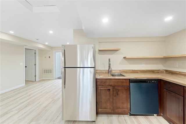 kitchen with sink, butcher block countertops, light hardwood / wood-style flooring, stainless steel fridge, and dishwashing machine