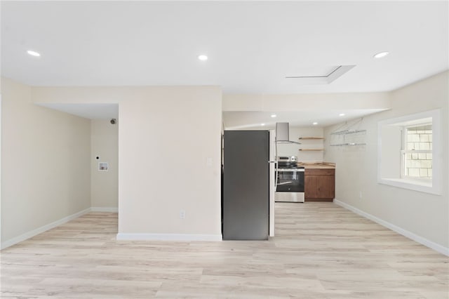 kitchen with appliances with stainless steel finishes, wall chimney range hood, and light wood-type flooring