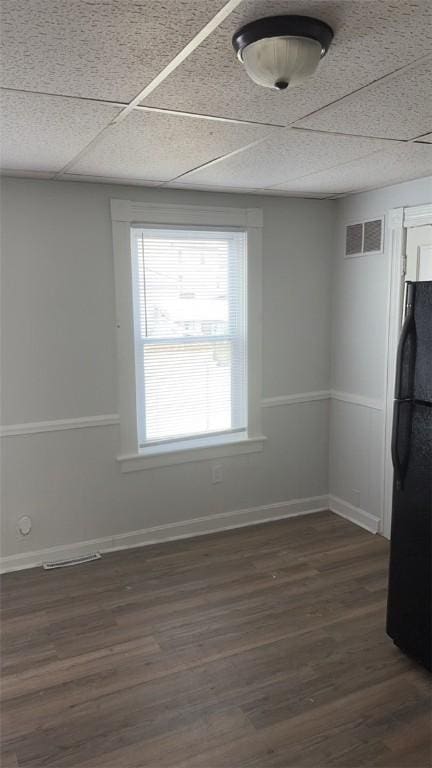 empty room featuring dark wood-type flooring and a paneled ceiling