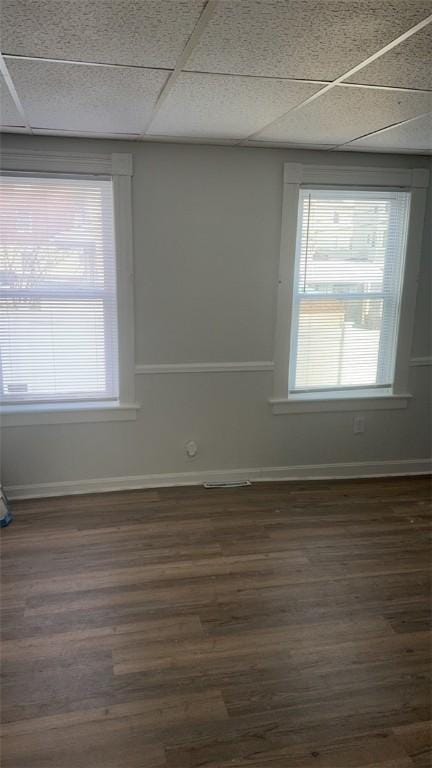 spare room with dark wood-type flooring, a paneled ceiling, and a wealth of natural light