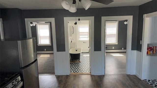 kitchen with plenty of natural light, a baseboard heating unit, and appliances with stainless steel finishes