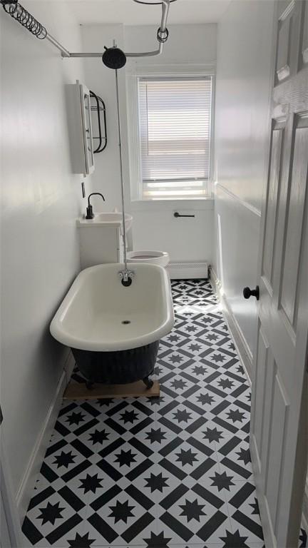 bathroom featuring toilet and a tub to relax in