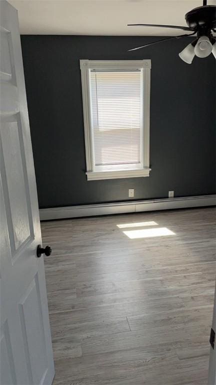 empty room with ceiling fan, a baseboard radiator, and light wood-type flooring