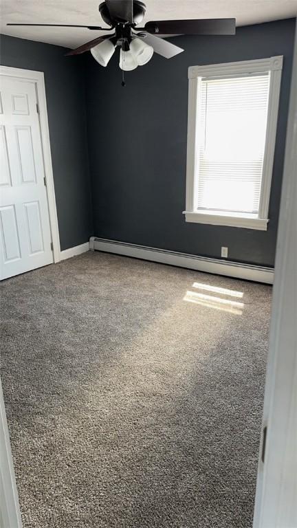 carpeted empty room with a baseboard radiator and ceiling fan