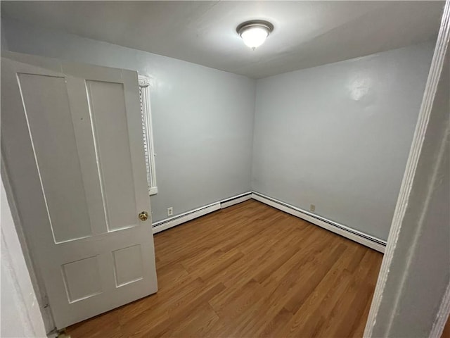 unfurnished room featuring hardwood / wood-style flooring and baseboard heating