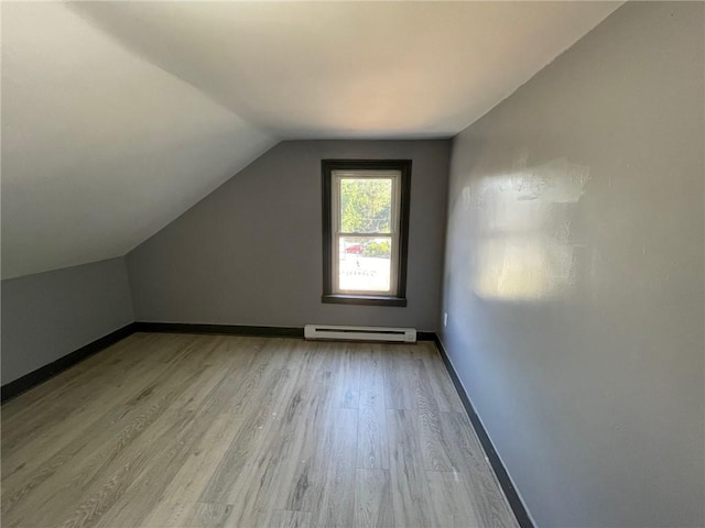 additional living space featuring baseboard heating, vaulted ceiling, and light hardwood / wood-style floors