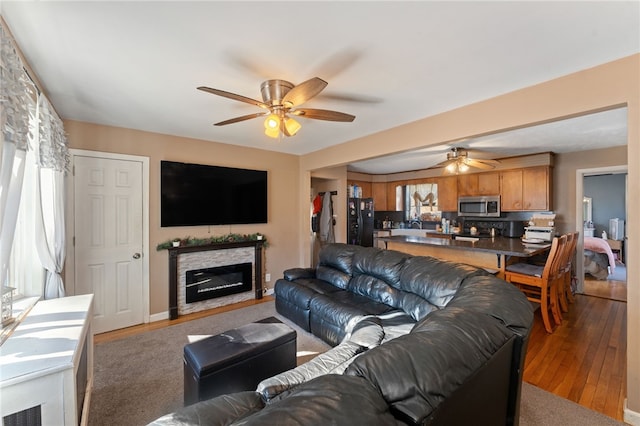 living room featuring ceiling fan, wood-type flooring, and a fireplace