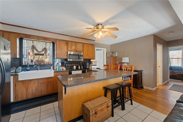 kitchen featuring light tile patterned flooring, a breakfast bar, sink, a center island, and black appliances