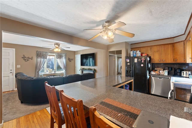 kitchen with light hardwood / wood-style floors, dishwasher, black refrigerator with ice dispenser, and a textured ceiling