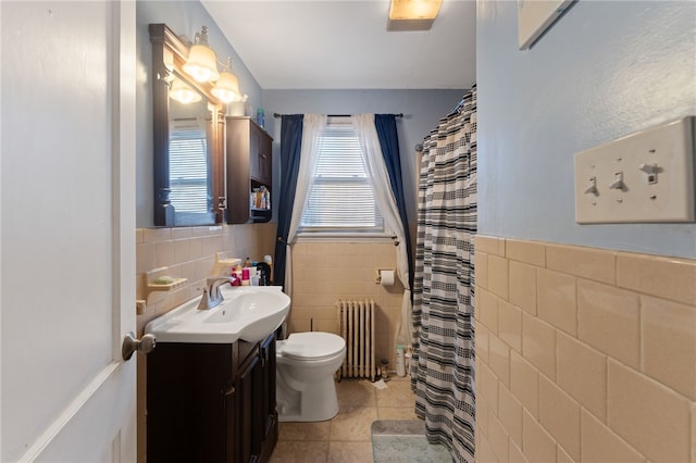 bathroom with tile patterned floors, toilet, tile walls, radiator heating unit, and vanity