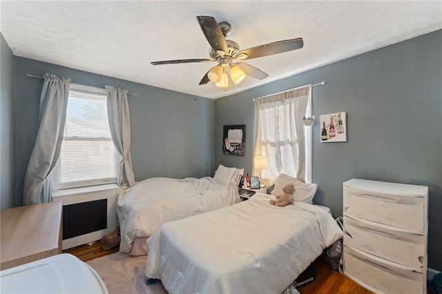 bedroom with radiator, hardwood / wood-style floors, and ceiling fan