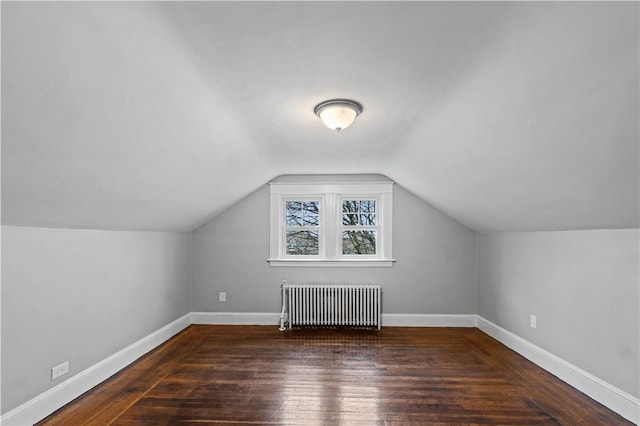 additional living space featuring lofted ceiling, radiator, and dark hardwood / wood-style floors