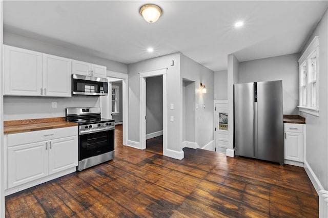 kitchen featuring white cabinetry, stainless steel appliances, dark hardwood / wood-style floors, and butcher block counters