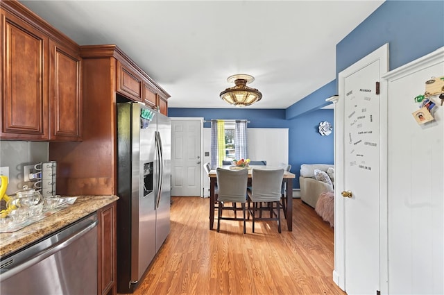 kitchen featuring light stone counters, a baseboard heating unit, light hardwood / wood-style flooring, and stainless steel appliances