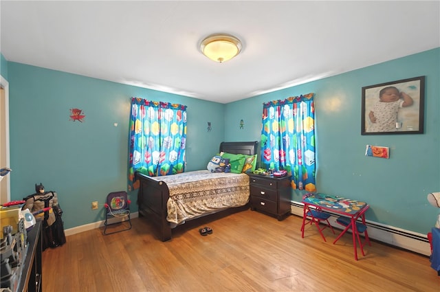 bedroom with baseboard heating and light hardwood / wood-style flooring