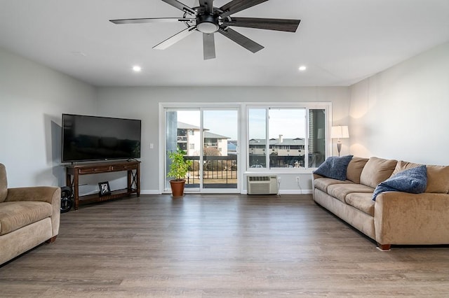 living room with hardwood / wood-style flooring, ceiling fan, and a wall mounted air conditioner