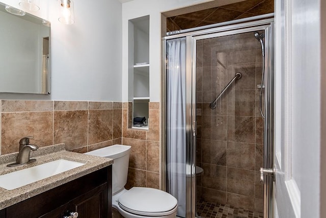 bathroom featuring tile walls, vanity, a shower with shower door, and toilet