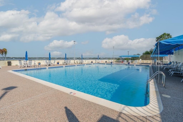 view of pool featuring a water view and a patio area