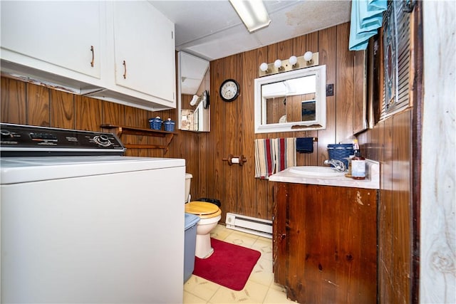 laundry area featuring washer / clothes dryer, a baseboard radiator, sink, and wood walls