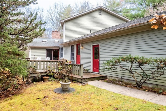 back of house featuring a wooden deck and a lawn