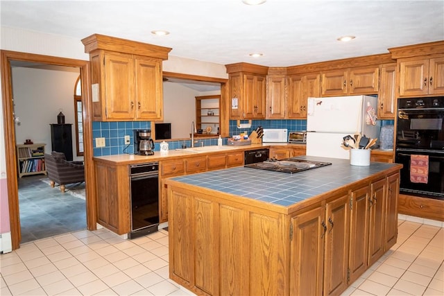 kitchen featuring a kitchen island, tasteful backsplash, sink, tile counters, and black appliances