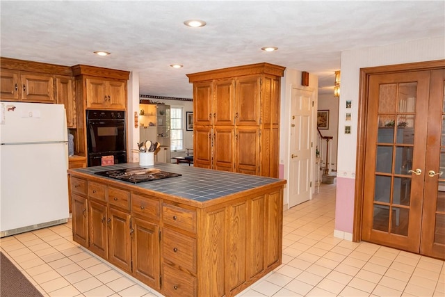 kitchen featuring tile countertops, a center island, light tile patterned floors, and black appliances