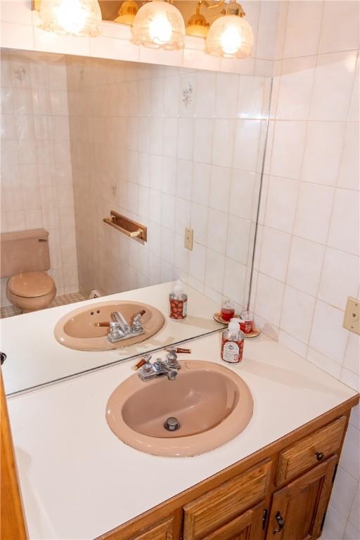 bathroom with tile walls, vanity, and toilet