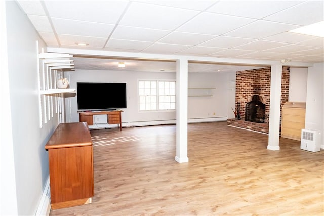 basement with a drop ceiling, hardwood / wood-style floors, and a brick fireplace