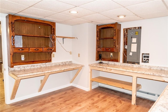 kitchen featuring a paneled ceiling, electric panel, and light hardwood / wood-style floors