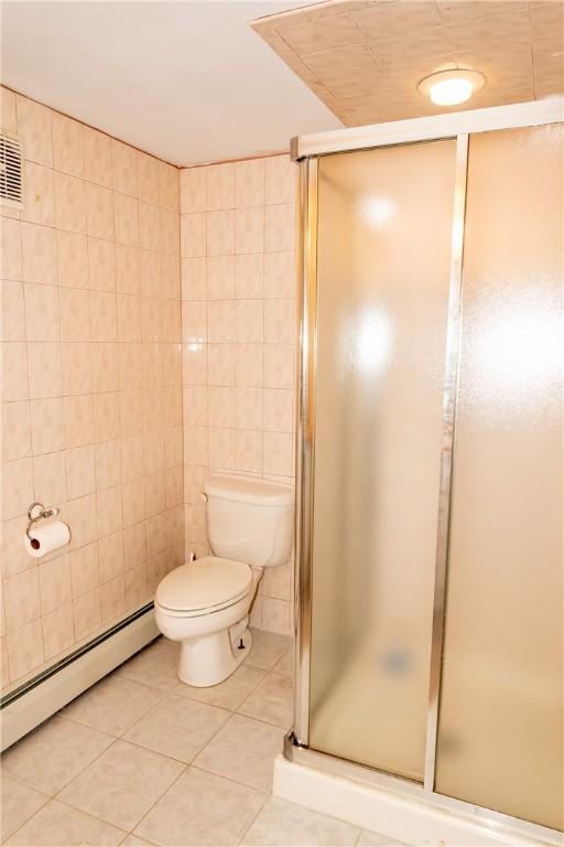 bathroom with tile patterned flooring, a baseboard heating unit, tile walls, and an enclosed shower