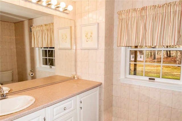 bathroom with vanity, tile walls, and toilet