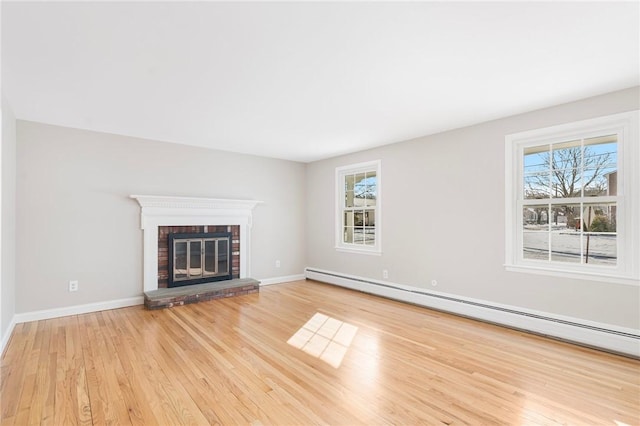 unfurnished living room featuring a brick fireplace, baseboard heating, and light hardwood / wood-style floors