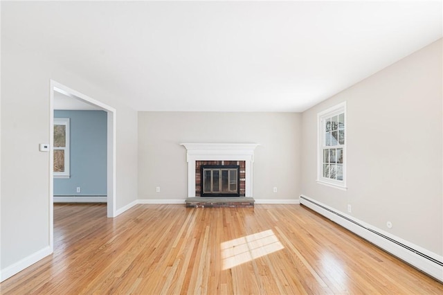 unfurnished living room with a baseboard heating unit, light hardwood / wood-style flooring, and a fireplace